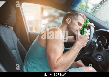 Autista ubriaco bere dietro al volante di una vettura Foto Stock