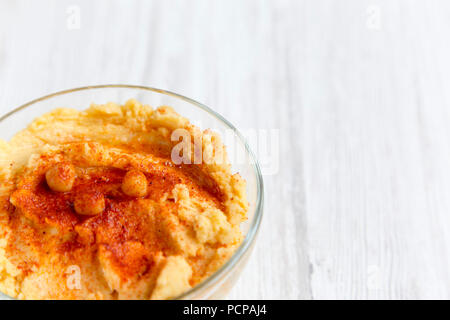 Ciotola di hummus con spezie su una bianca superficie di legno e a basso angolo. Close-up. Copia dello spazio. Foto Stock