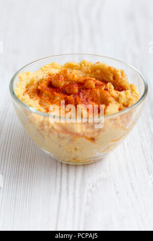 Ciotola di hummus con ceci arrosto, paprica, olio d'oliva su una bianca tavolo in legno e a basso angolo. Primo piano. Foto Stock