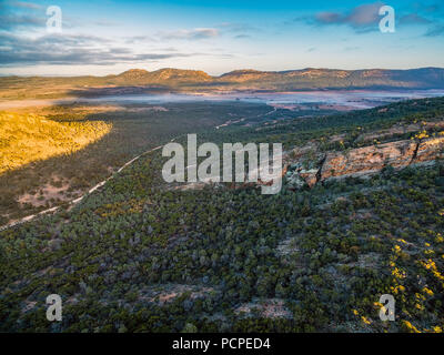 Strada sterrata avvolgimento attraverso colline e vegetazione nativa a sunrise - Flinders Ranges, Sud Australia Foto Stock