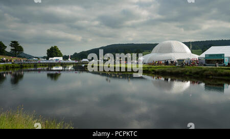 RHS Chatsworth Flower Show showground (persone che visitano, marquee, tende, grande cupola del Conservatorio & bridge si riflette nel fiume) Derbyshire, Inghilterra, Regno Unito. Foto Stock