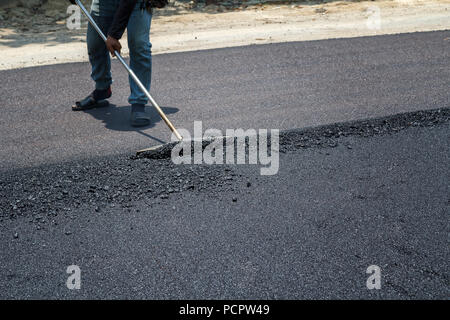 Lavoratori su asfaltatura lastricatore macchina durante la strada lavori di riparazione Foto Stock