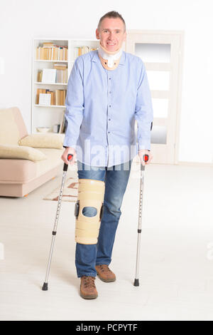 Uomo con gamba in collo ortesi per ginocchio e gabbie di stampelle per la stabilizzazione e il supporto Foto Stock