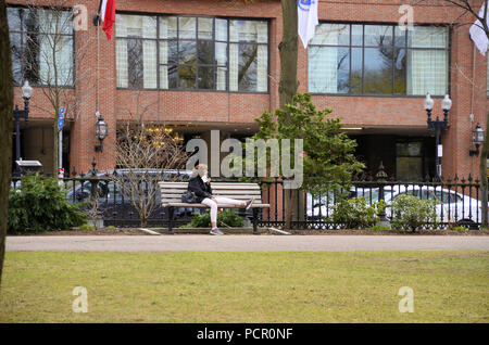 Lone donna più anziana in appoggio la gamba su un Boston Public panchina da giardino a Boston, Massachusetts, Stati Uniti. Foto Stock
