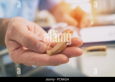 Medico audiologist azienda protesi nella sua mano Foto Stock