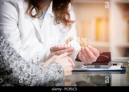 Medico mostrando audizione aiuto al suo paziente nell'ufficio del medico Foto Stock