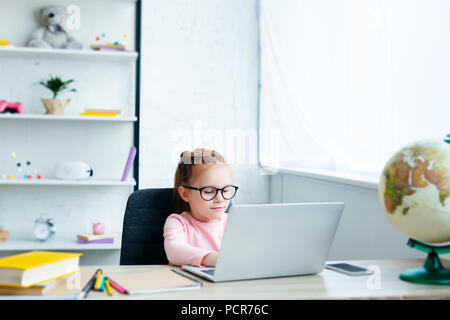 Bella dai capelli rossi schoolgirl utilizzando computer portatile mentre lo studio a casa Foto Stock