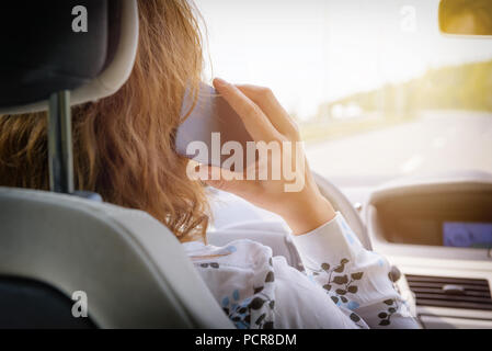 Donna che utilizza il telefono mentre si guida la macchina. Rischiosi comportamenti di guida concept Foto Stock