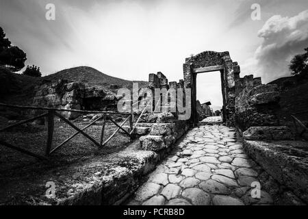 Strada di ciottoli che conduce attraverso una sorta di porta verso il centro della città di antiche città di Pompei e vicino a Napoli, Italia Foto Stock