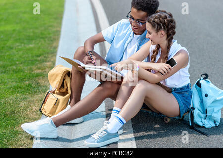 Multietnica ragazzo adolescente e una ragazza studiare insieme in posizione di parcheggio Foto Stock