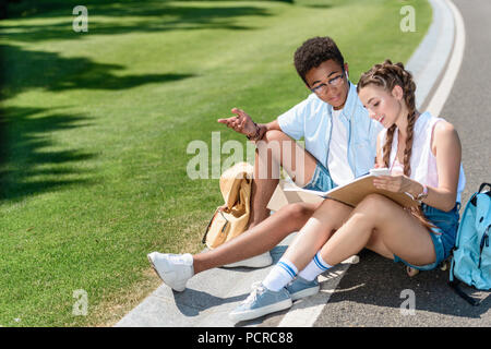 Elevato angolo di visione della società multietnica ragazzo adolescente e una ragazza studiare insieme in posizione di parcheggio Foto Stock