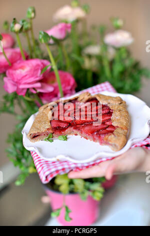 torta aperta con fragole. in penne per bambini. decorazione del balcone con fiori freschi. fiori rosa. Foto Stock