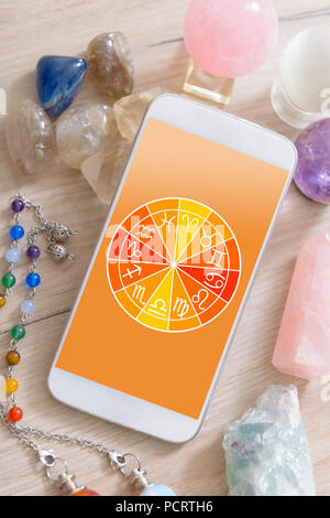 Segni zodiacali e smart phone con cristalli. Concetto moderno di astrologia. Foto Stock