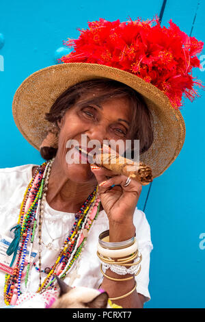 Vecchia donna cubana fuma un sigaro cubano sulla strada e pone con il suo gatto per i turisti, La Habana, Cuba, Caraibi, America centrale, La Habana, Cuba Foto Stock