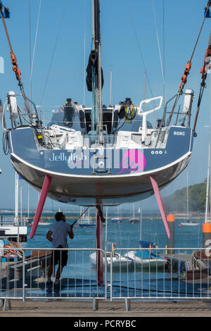 Un grande yacht racing di essere puliti con una idropulitrice a Cowes yacht haven in una barca o un paranco sollevatore sull'isola di Wight. Foto Stock