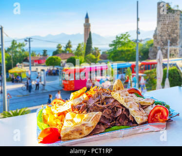 Gustosa Döner Kebab con beaf, focacce, patatine fritte e verdure in terrazza estiva del ristorante, situato nel quartiere di Kaleici, Antalya, Turchia. Foto Stock