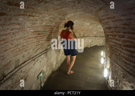 Un turista a piedi giù i passaggi all'interno della Torre Bianca di Salonicco, Grecia, e ascoltando il tour del museo Foto Stock