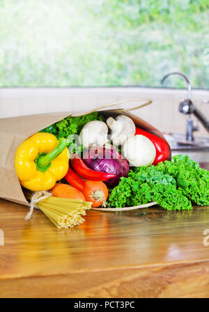 Organico fresche verdure crude Consegna del cibo nel sacchetto di carta sul banco di legno in cucina Foto Stock