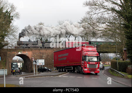 LSWR T9 classe motore a vapore n. 30120, costruito nel XIX secolo, attraversa il mattone arco all'Butts, Alton come un XXI secolo autocarro passa al di sotto di Foto Stock