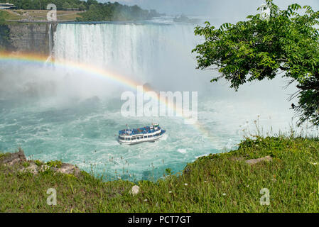 Niagara Falls, Ontario, Canada. Vista delle Cascate Ferro di Cavallo Canadesi in estate, tour in barca la Domestica della Foschia sotto un arcobaleno sul Fiume Niagara. Foto Stock