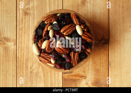 Mix di noci pecan, nero uvetta jumbo, mirtilli, mandorle senza buccia in bambù ciotola sul tavolo di legno. Primo piano Foto Stock