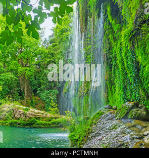 Il bagnato massi nel lago di Kursunlu cascata circondata da lussureggiante foresta verde, Aksu, Turchia. Foto Stock