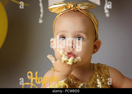 Close up adorabile bambina divorando la torta con le mani Foto Stock