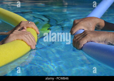 Matura in piscina, affacciati, galleggiante con piscina tagliatelle, messa a fuoco selettiva su mani tenendo le tagliatelle Foto Stock