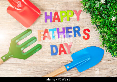 Felice Festa del papà lettere in legno con il lavoro degli attrezzi del giardino su sfondo di legno. Saluti e presenta Foto Stock