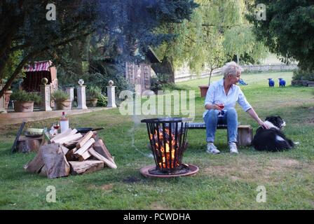 Giovane donna bionda si siede con il suo Border Collie dal fuoco Foto Stock