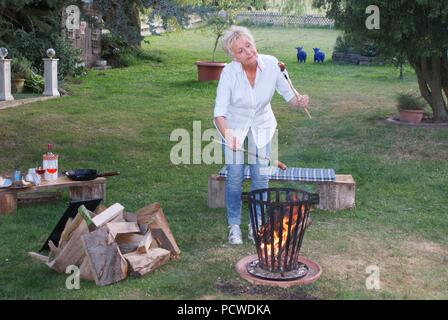 Con appetito la donna guarda le salsicce alla griglia Foto Stock