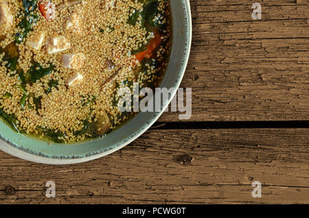 Gustosa zuppa di pesce con i semi di sesamo nel verde della piastra di porcellana su sfondo grigio. La cucina giapponese. Foto Stock