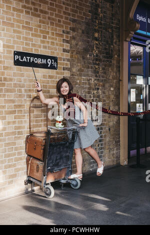 La gente di scattare le foto da 9 3/4 Piattaforma interna alla stazione di King Cross, Londra, stazione dove gli studenti della scuola di Hogwarts cattura l'Hogwarts Express. Foto Stock