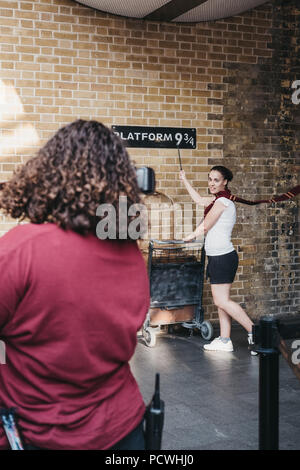 La gente di scattare le foto da 9 3/4 Piattaforma interna alla stazione di King Cross, Londra, stazione dove gli studenti della scuola di Hogwarts cattura l'Hogwarts Express. Foto Stock