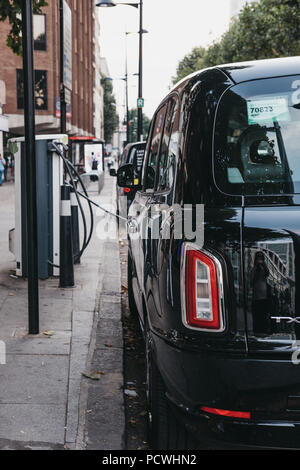 Nuovo LEVC elettrico TX London Black Cab ricarica dal punto di modifica su una strada di Londra, Regno Unito. Foto Stock