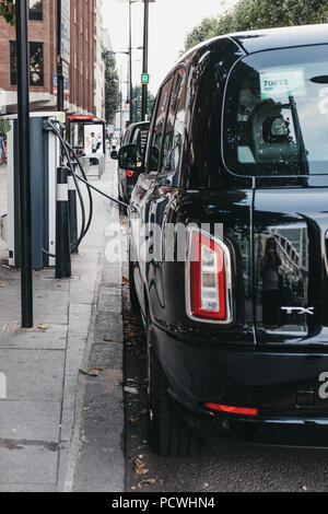 Nuovo LEVC elettrico TX London Black Cab ricarica dal punto di modifica su una strada di Londra, Regno Unito. Foto Stock