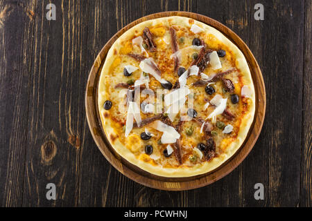 Pizza Siciliana con acciughe e pomodori secchi su tavola di legno, vista da sopra Foto Stock