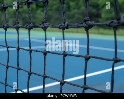 Vista ingrandita del campo da tennis maglie di rete con tribunali sfocate in background Foto Stock