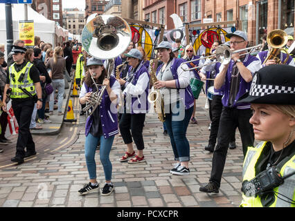 Glasgow, Scotland, Regno Unito. 04 agosto 2018. Gli ufficiali di polizia di accompagnare i partecipanti al Corteo di carnevale del Merchant City Festival. Sono mostrate le Baybeat street band, e dietro di loro persone che trasportano 'stained finestre di vetro' del Mackintosh Rose. Il festival è parte del Festival 2018 una città-ampia manifestazione culturale in esecuzione in parallelo con il Glasgow 2018, i campionati europei. Credito: Elizabeth Leyden/Alamy Live News Foto Stock