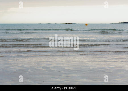 Le acque calme come il sole scende oltre il mare Foto Stock