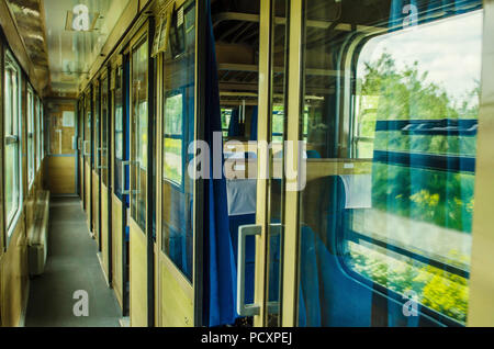 Macchina vuota del treno della lunga distanza messaggio. All'interno della vecchia rete ferroviaria pubblica cabina treno con sedili, corrimano, ventola e interni in stile vintage Foto Stock