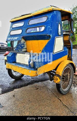 Colorista tricicli sono un mezzo comune di trasporto pubblico nel paese. Qui uno di attesa per i passeggeri si è fermato a parking lot-Chocol Foto Stock