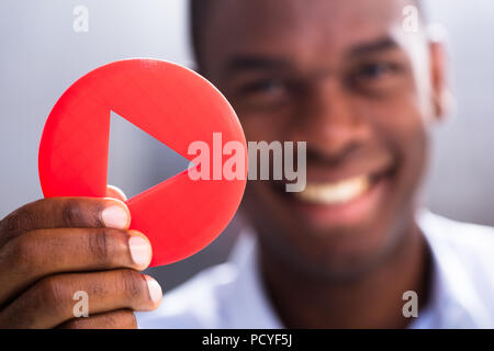 Close-up di happy businessman Holding rosso pulsante Riproduci Foto Stock