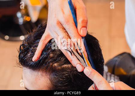 Barbiere cesoie i capelli sulla sua testa con le forbici. Taglio di capelli di close-up. Barbiere. Foto Stock