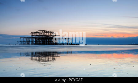 Le rovine del Molo Ovest di Brighton al tramonto e una bassa marea a molla Foto Stock