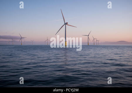 Sulle turbine eoliche offshore all'alba nel mare d'Irlanda, Regno Unito, con il Parco nazionale del Lake District visto in lontananza Foto Stock