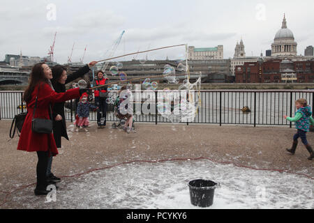 Due giovani coreani signore hanno divertimento sul fiume Tamigi Embankment nei pressi della Cattedrale di St Paul a Londra a giocare con bolle Foto Stock