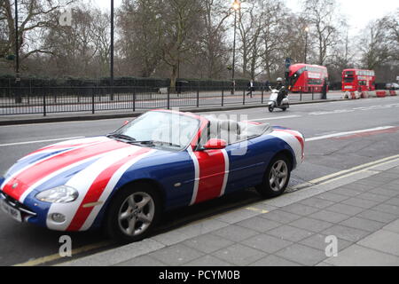 Tipo Cabriolet sport Unione Jack dipinto auto parcheggiate a Park Lane Near Grosvenor House Hotel sulla gelida giornata invernale, con due carrozze a due piani in background Foto Stock