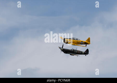 Uno Spitfire e North American Aviation T-6 Texano Harvard in volo a fianco a fianco Foto Stock