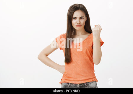 Indignato timida ragazza che vogliono rispettare. Piscina colpo di offeso sconvolto carino donna in t-shirt, tenendo la mano sul hip e sollevamento di pugno chiuso, frowni Foto Stock